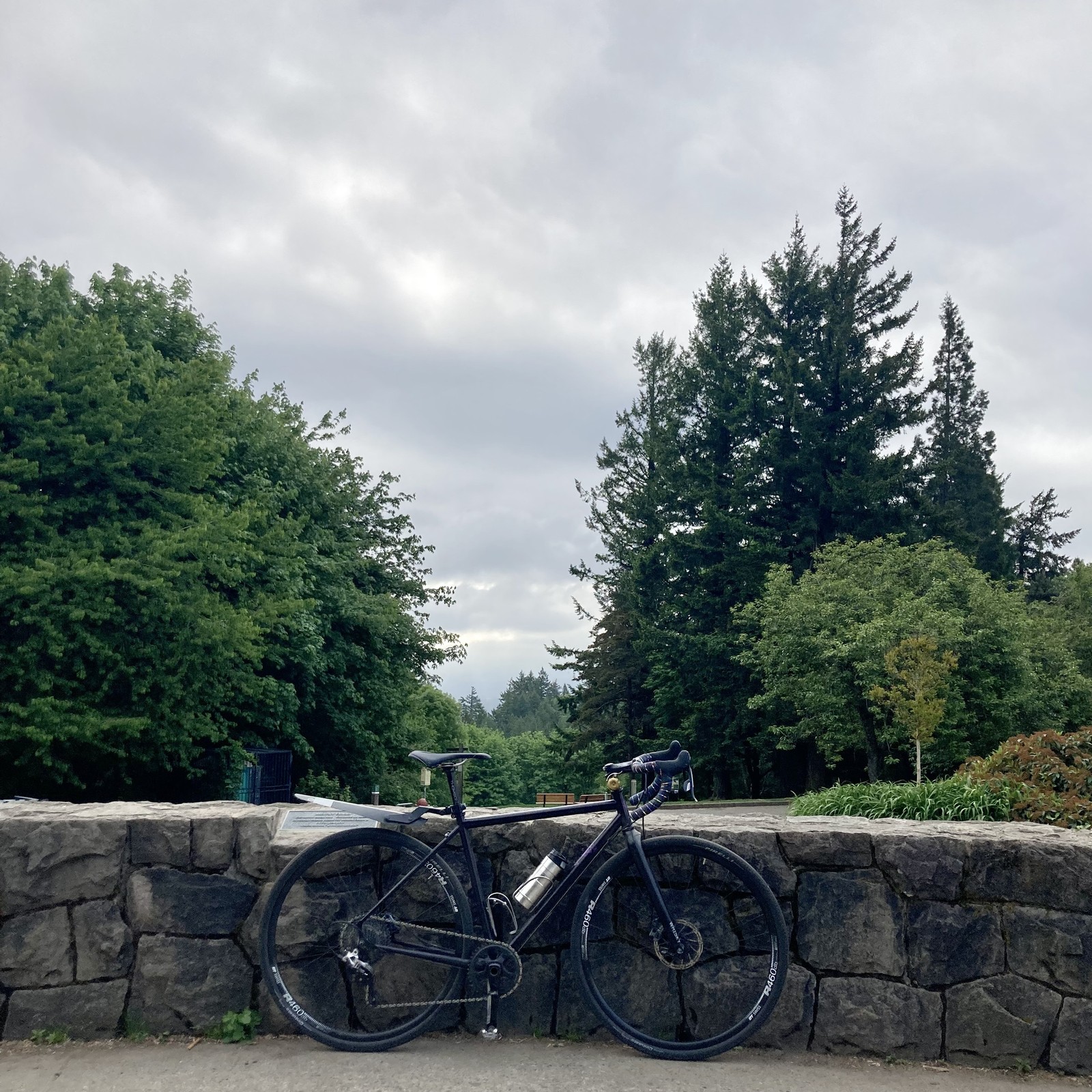 View from Council Crest Park toward Mt. Hood, which is hidden by marine haze and a layer of low altitude stratus clouds. In the foreground, a bicycle leans against a low stone wall.
