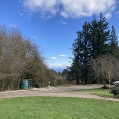 The very tiptop of Mt. Hood peaks out from a low deck of fluffy white clouds. Clear sky between us and the mountain; another deck of clouds overhead moving east